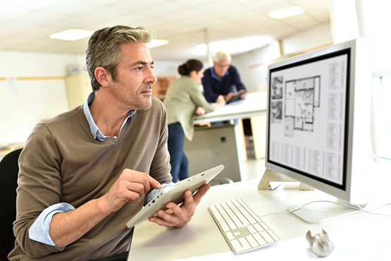 Engineer working in design office on desktop computer Vergabe Bauauftrag an Baufirma
